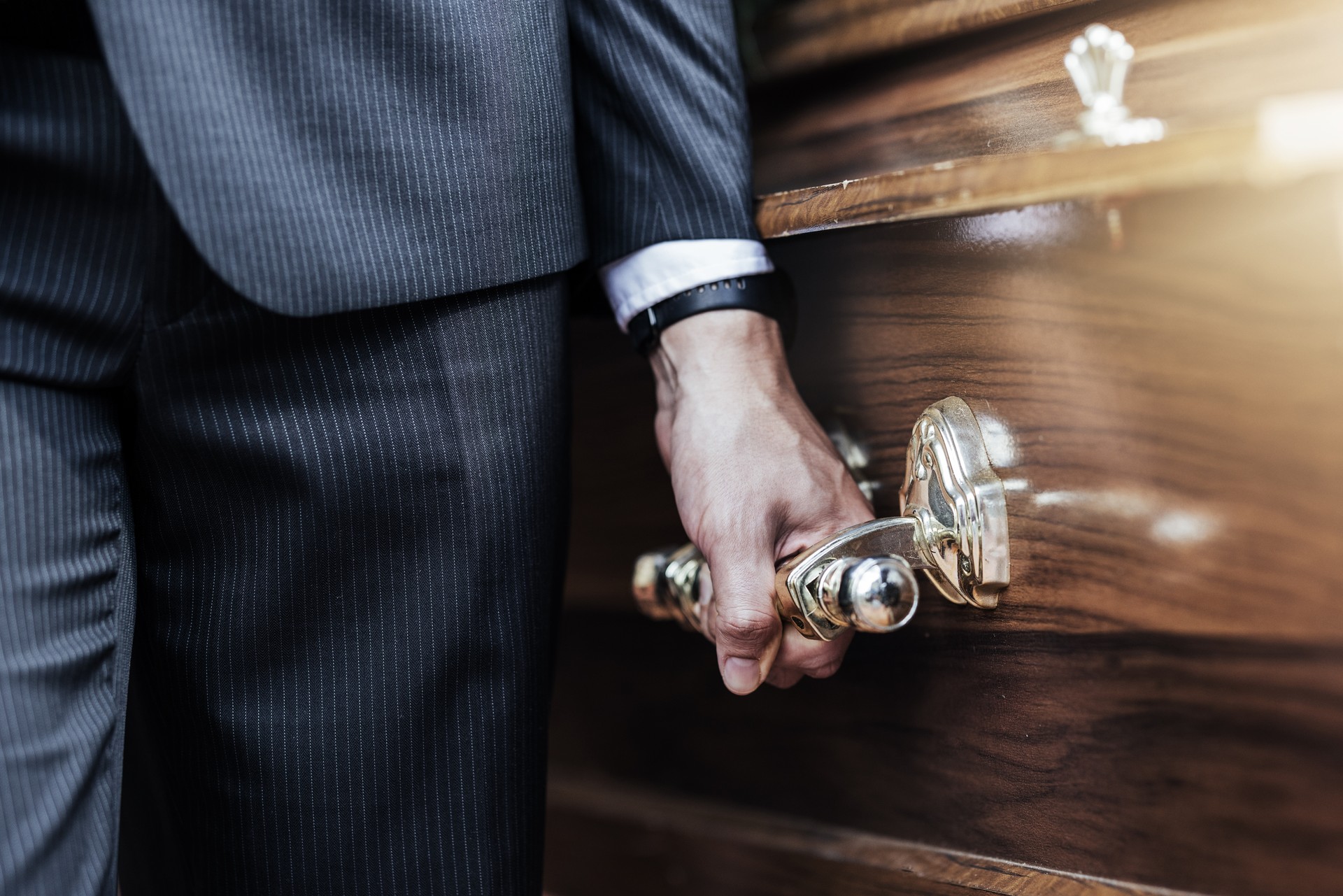 Funeral, man hands and holding coffin at a sad, death and church even of a person with casket. Support, loss and dead burial of a male at a religion, respect and mourning ceremony with a suit