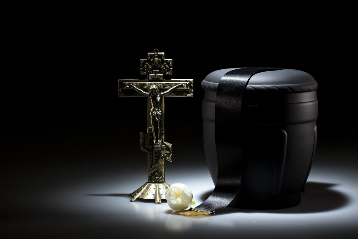 black funerary urn with orthodox cross on dark background